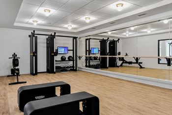 A gym with a variety of equipment including a treadmill, a stationary bike, a rowing machine, a squat rack, a bench press, a cable machine, a leg press, a pull up bar, a